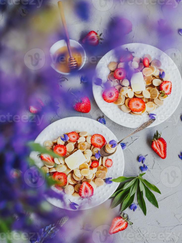 Pancake cereal, trendy food. Mini cereal pancakes with butter, honey, and strawberries. photo