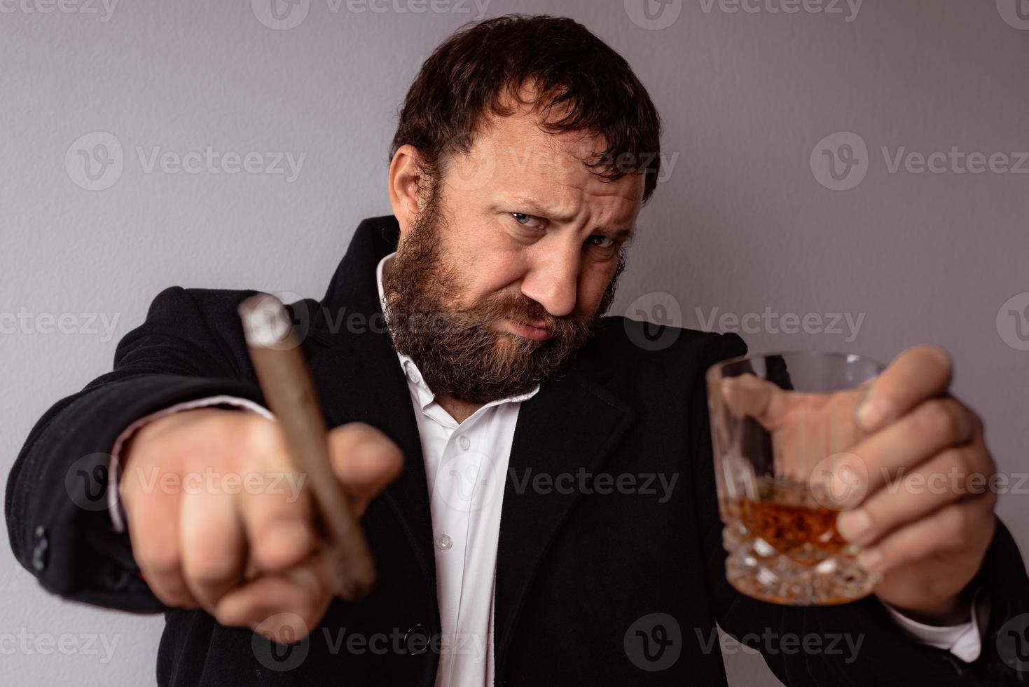 Hombre barbudo en abrigo moderno y camisa fumando su cigarro foto