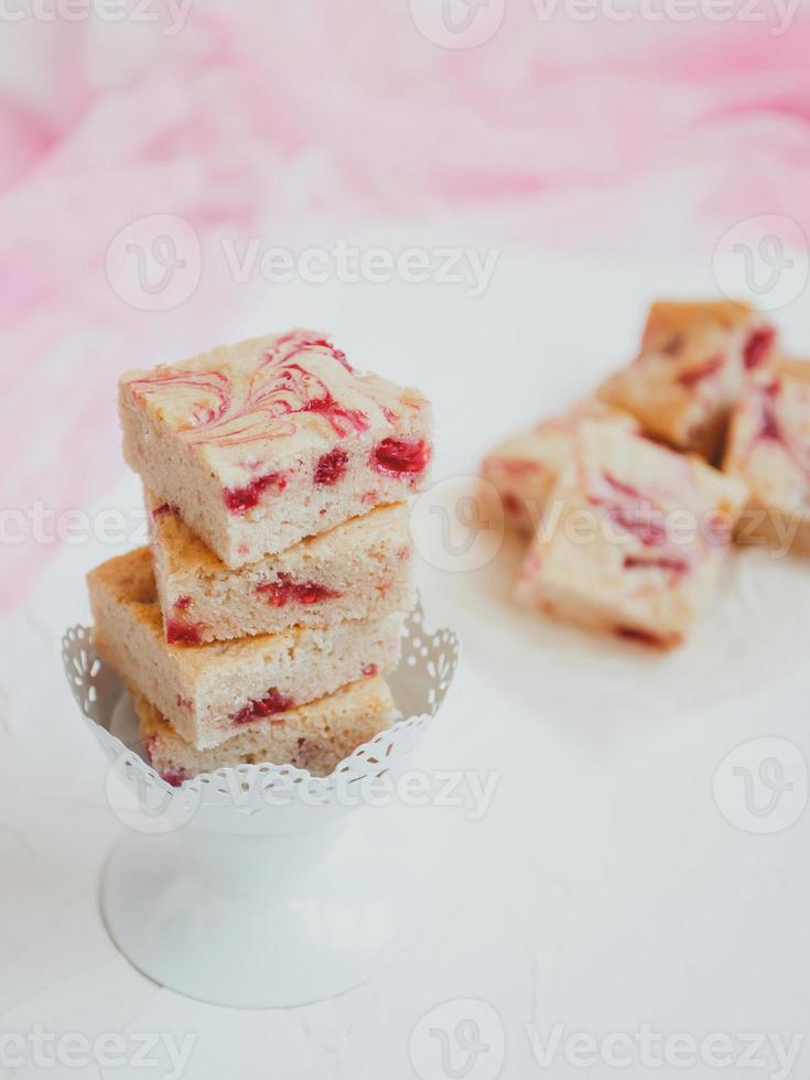 Blondies caseras, hechas de chocolate blanco con frambuesas frescas, sobre un fondo claro. foto