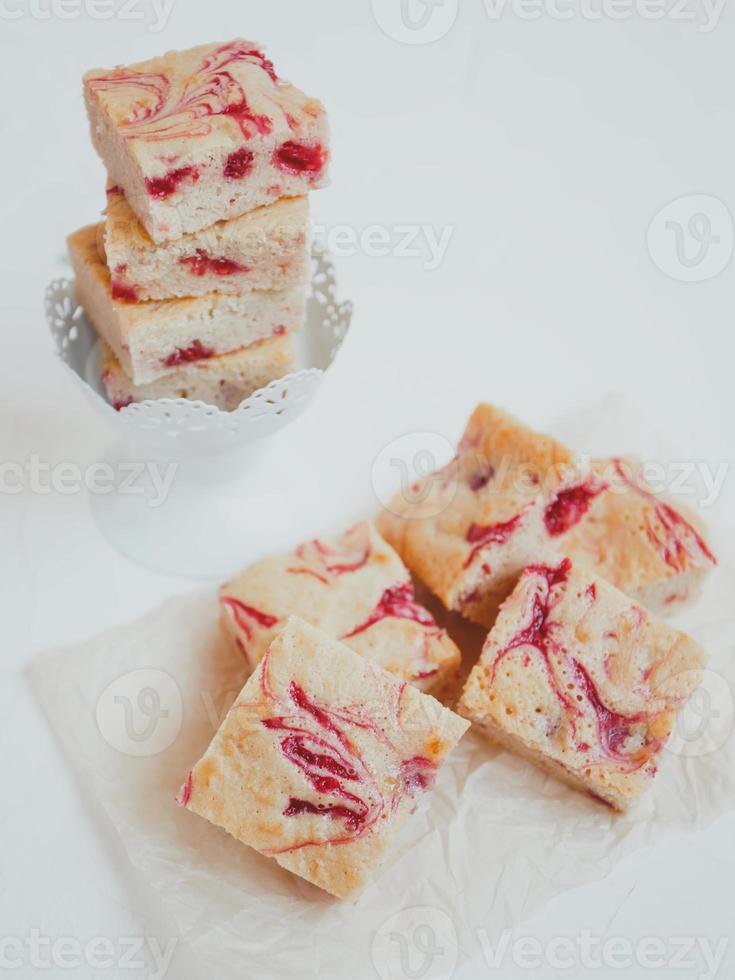 Blondies caseras, hechas de chocolate blanco con frambuesas frescas, sobre un fondo claro. foto