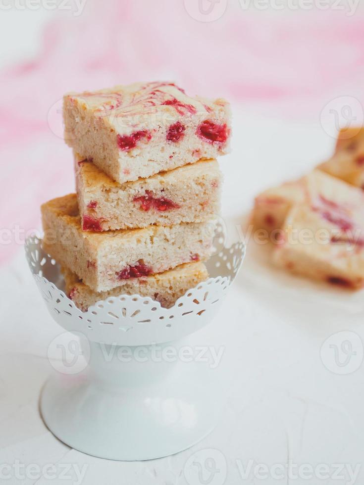 Blondies caseras, hechas de chocolate blanco con frambuesas frescas, sobre un fondo claro. foto