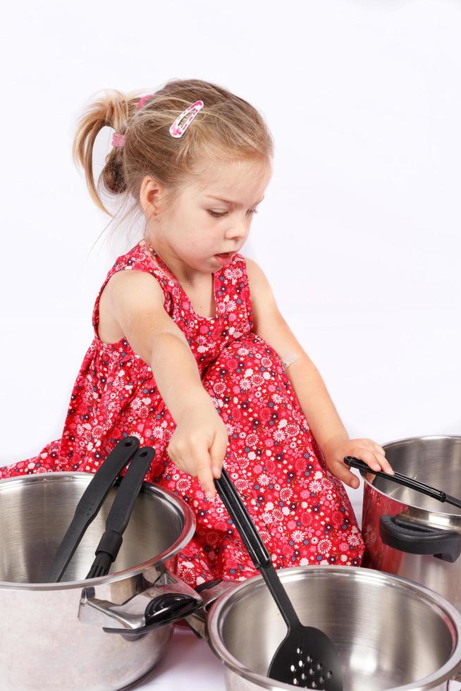 niño pequeño usando accesorios de cocina divirtiéndose foto