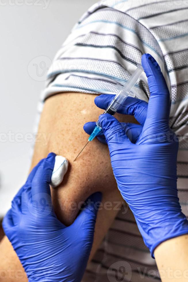 A doctor vaccinates a man against coronavirus at a clinic. Close-up. The concept of vaccination, immunization, prevention against Covid-19. photo