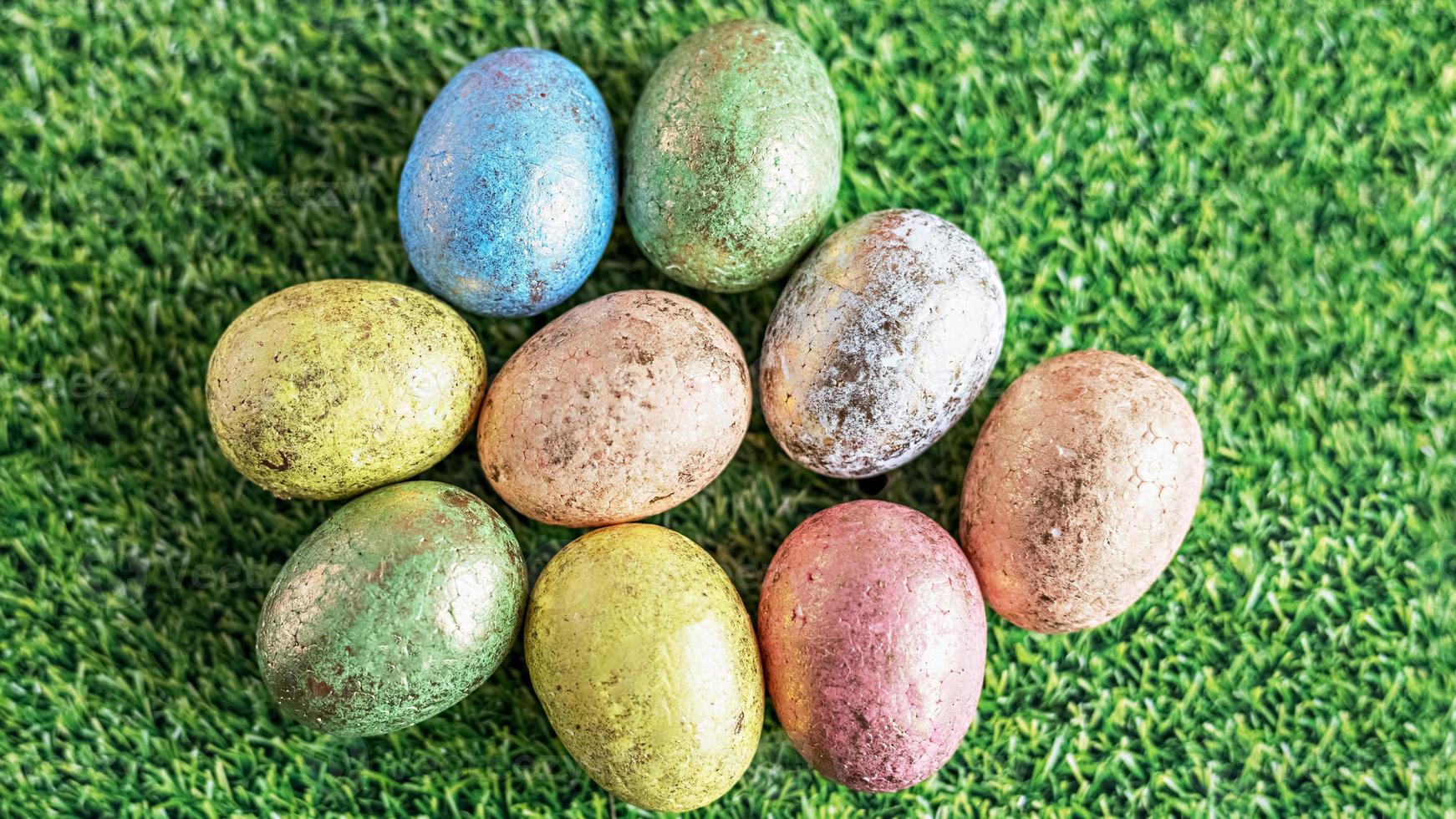 huevos de pascua en colores pastel sobre un fondo verde con textura de hierba. vista desde arriba foto
