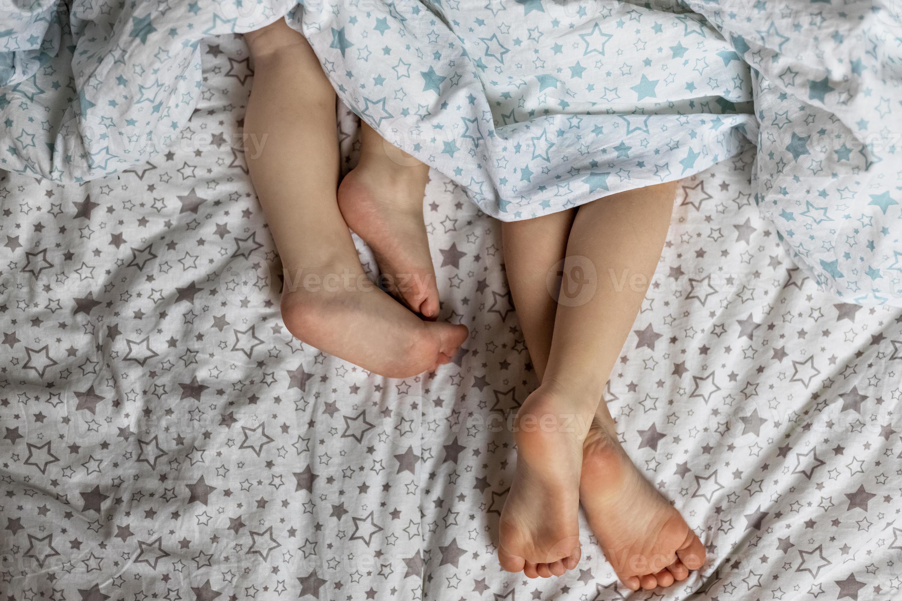 Girlys feet Close-up of two pairs of toddler girls feet on the bed under the blanket.  Light blue and beige tones. 2605488 Stock Photo at Vecteezy