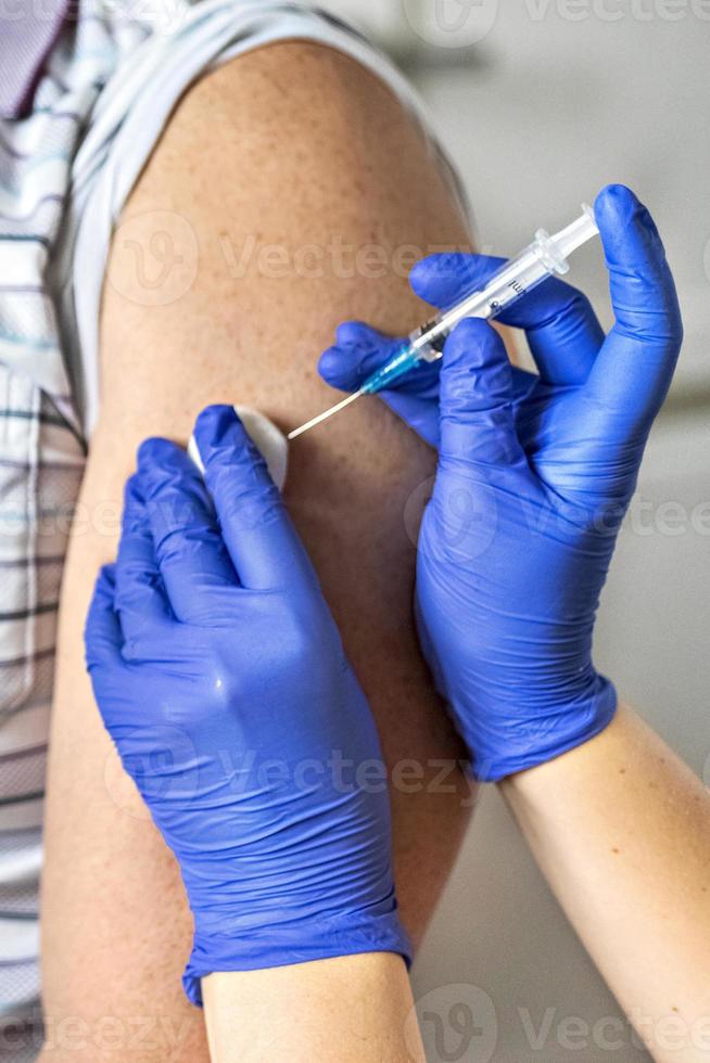 A doctor vaccinates a man against coronavirus at a clinic. Close-up. The concept of vaccination, immunization, prevention against Covid-19. photo