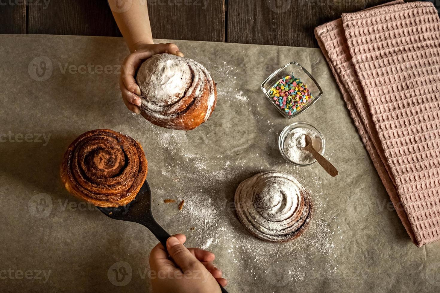 Children's hand takes a freshly baked cinnamon bun photo