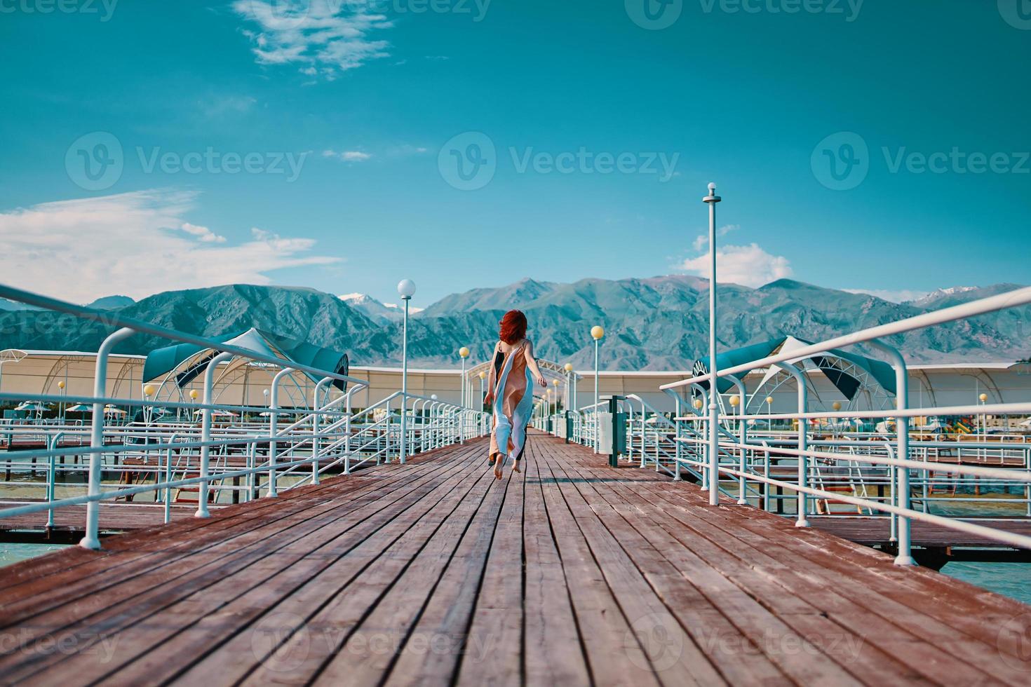 chica pelirroja corre a lo largo del muelle. foto