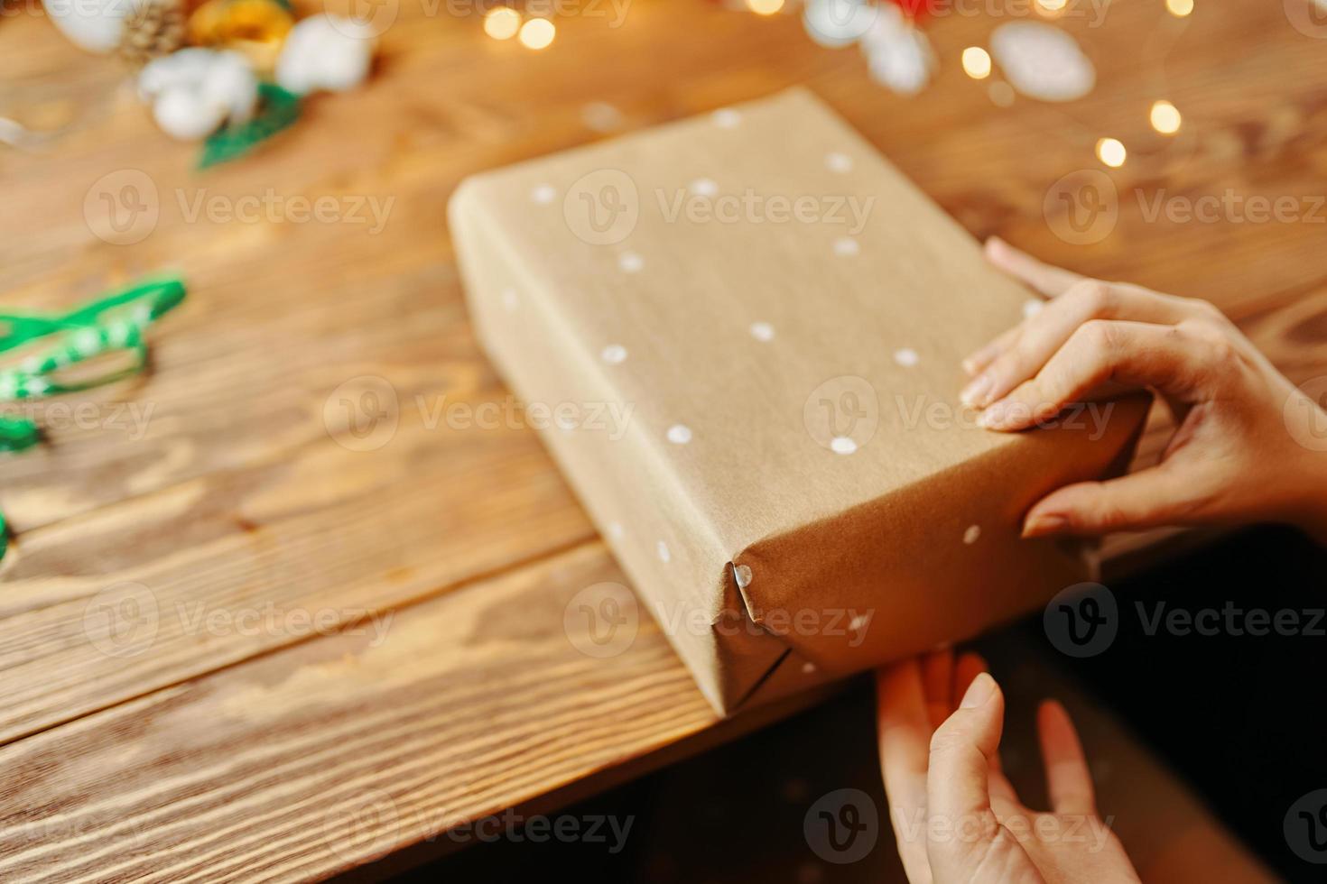 Close up of women's hands packing Christmas gift. photo