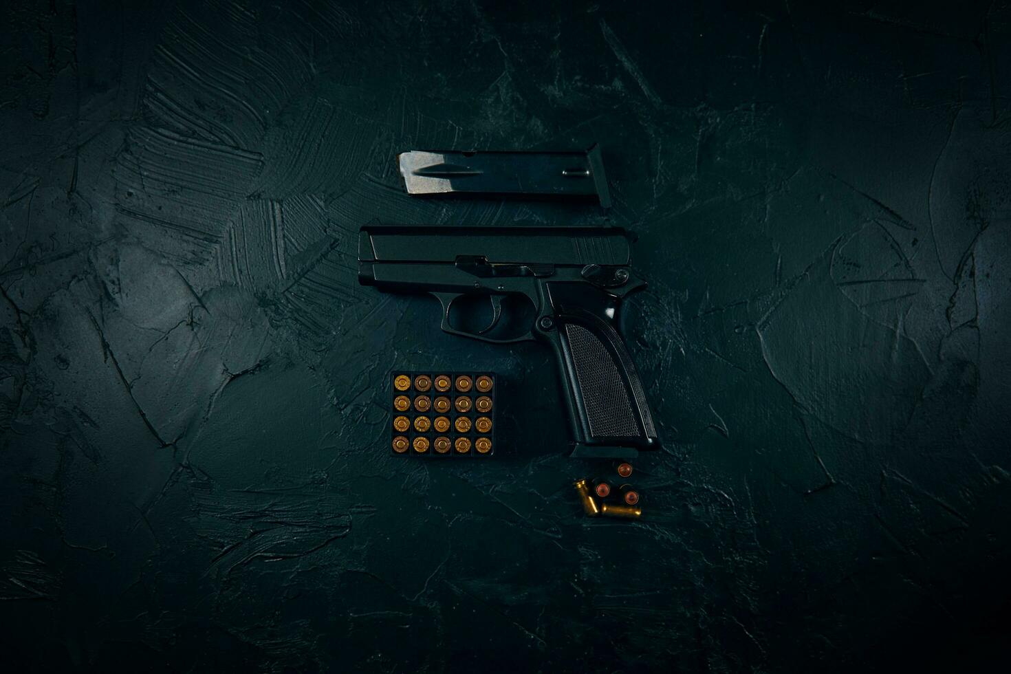pistola con cartuchos en la mesa de hormigón oscuro. foto