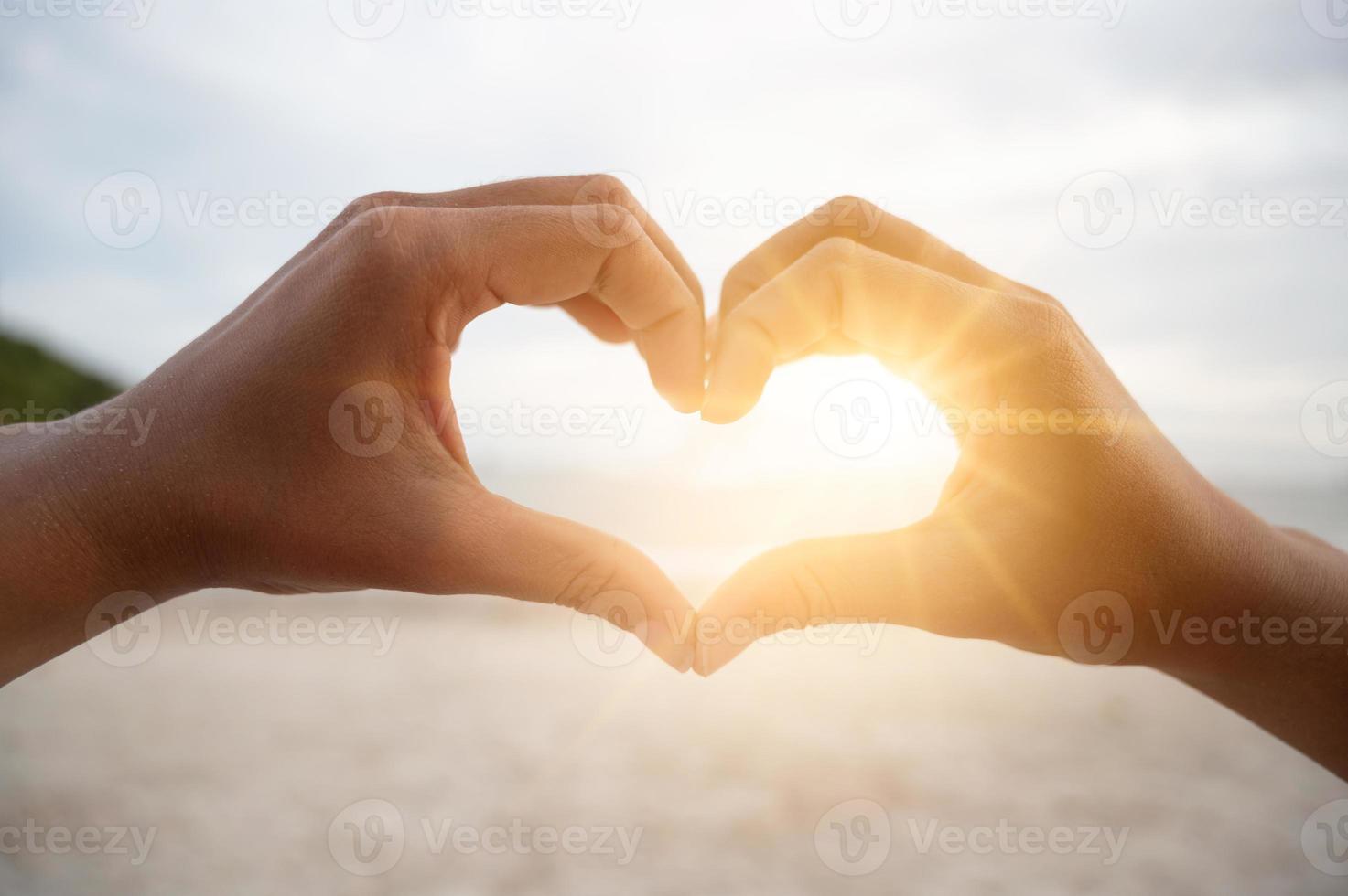 The hands of women and men are the heart shape with the sun light passing through the hands photo