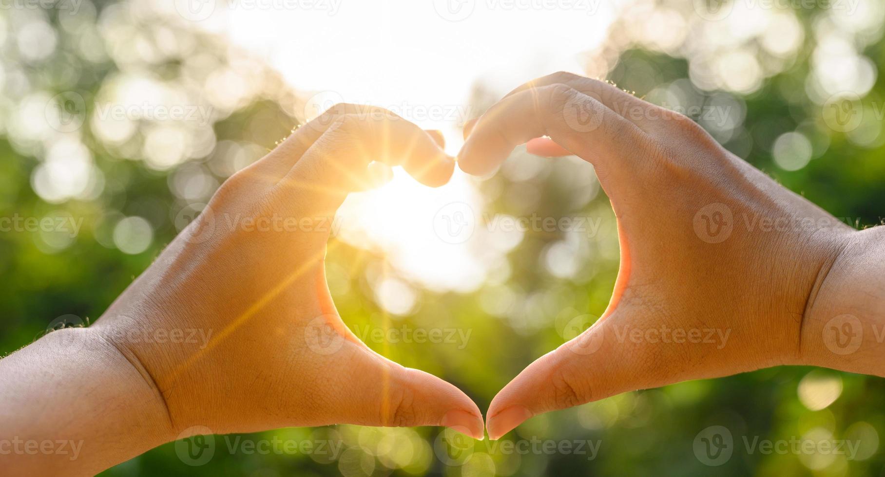 las manos de mujeres y hombres tienen forma de corazón con la luz del sol pasando a través de las manos foto