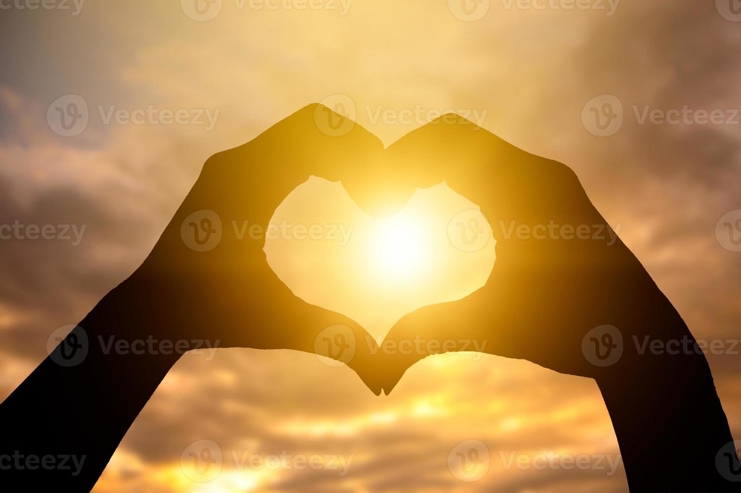 The hands of women and men are the heart shape with the sun light passing through the hands photo