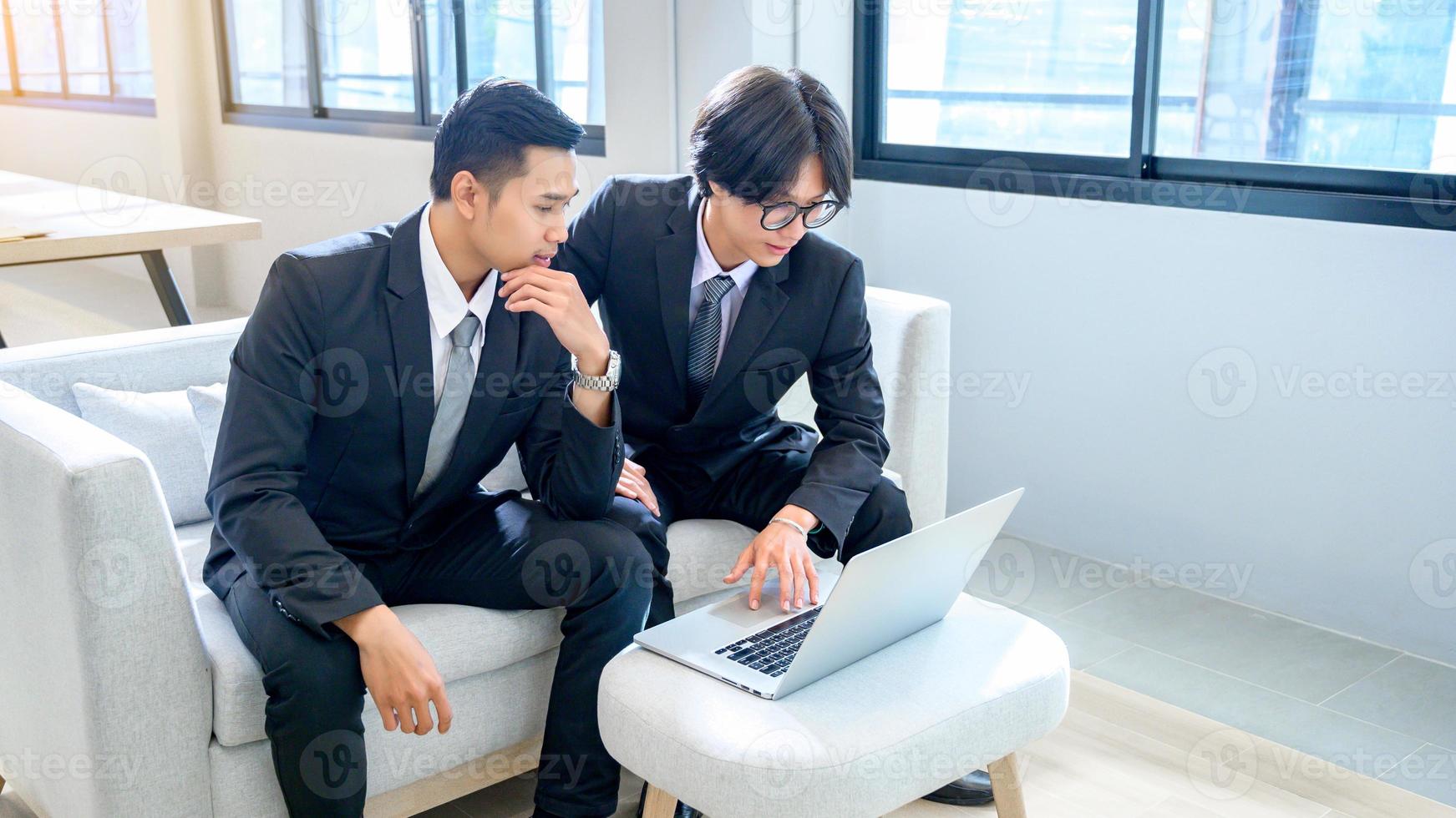 un grupo de 2 hombres de negocios trabajan seriamente con computadoras en la oficina. foto