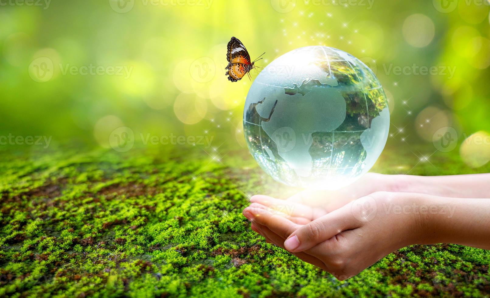 un hombre con un globo de cristal concepto día tierra salvar el mundo salvar el medio ambiente el mundo está en la hierba del fondo verde bokeh foto