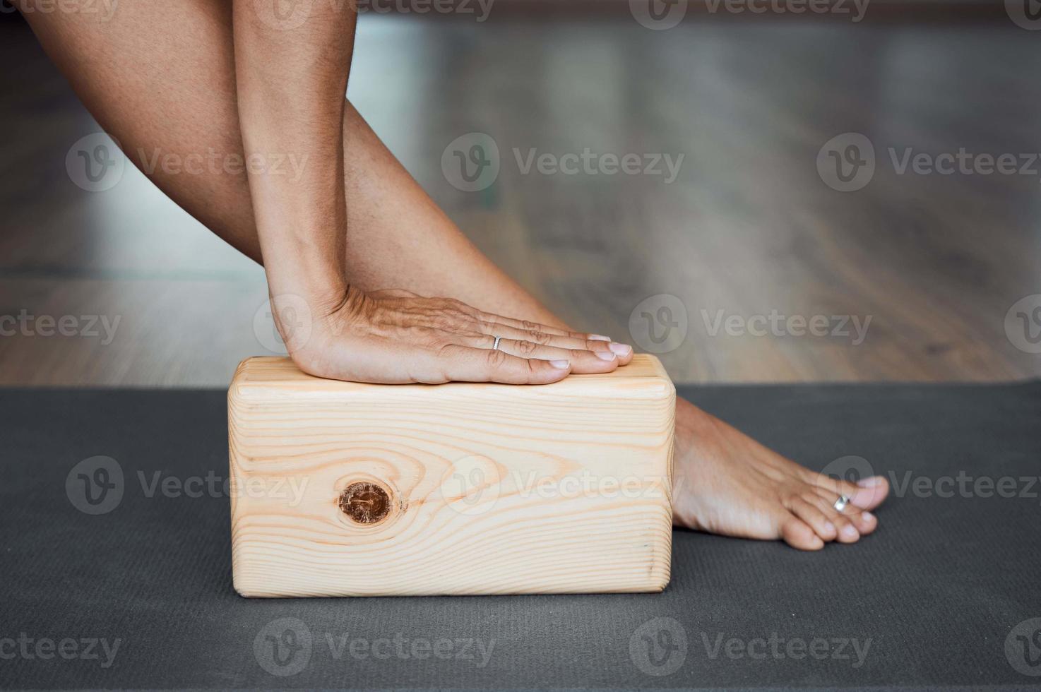 Pose de triángulo extendido con primer plano de ladrillo, pose de utthita trikonasana con bloque de madera en yoga iyengar en estudio foto