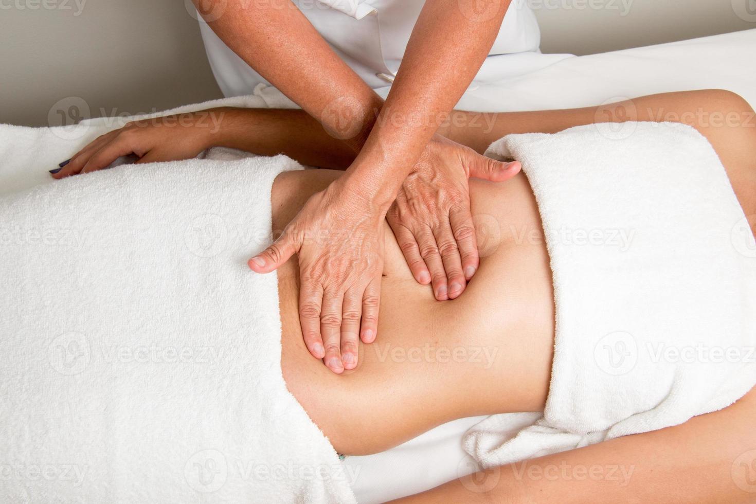terapeuta de masaje masajeando el estómago de una mujer foto
