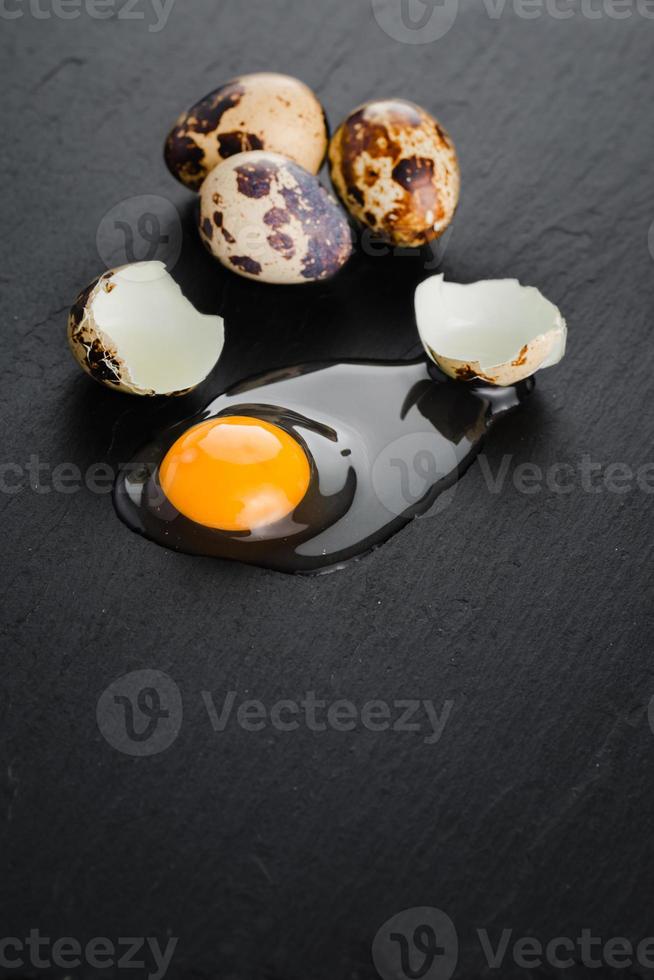 Quail eggs on black stone background, broken, cracked quail egg, yolk of quail egg. Organic product. photo