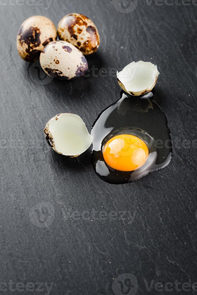 Quail eggs on black stone background, broken, cracked quail egg, yolk of quail egg. Organic product. photo