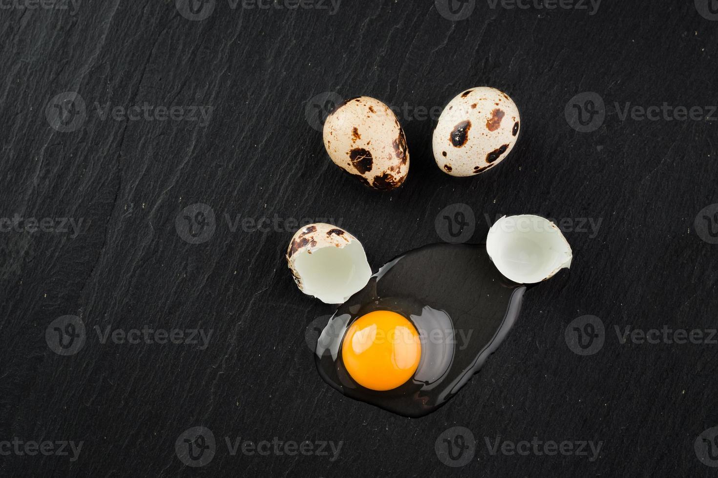Quail eggs on black stone background, broken, cracked quail egg, yolk of quail egg. Organic product. photo