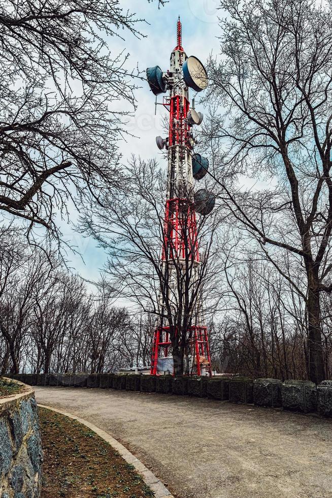 TV tower next to the asphalt road, dramatic sky, forest mountain old country road with stone fence. photo