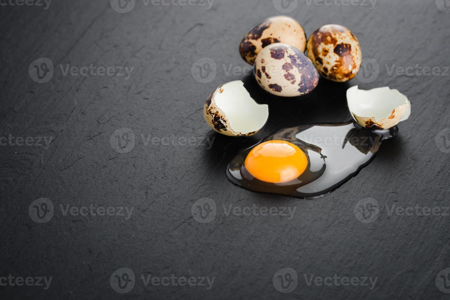 Quail eggs on black stone background, broken, cracked quail egg, yolk of quail egg. Organic product. photo