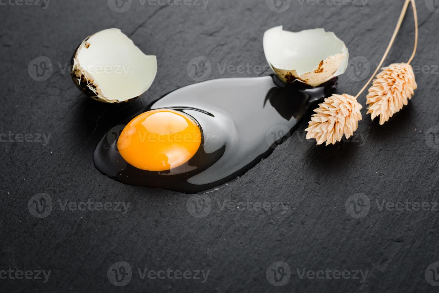 Quail eggs on black stone background, broken, cracked quail egg, yolk of quail egg. Organic product. photo