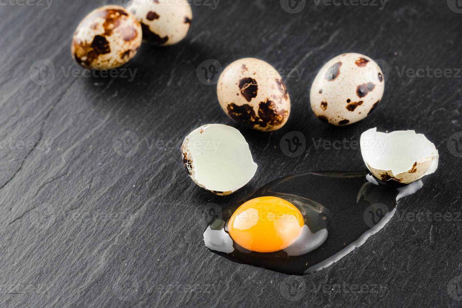 Quail eggs on black stone background, broken, cracked quail egg, yolk of quail egg. Organic product. photo