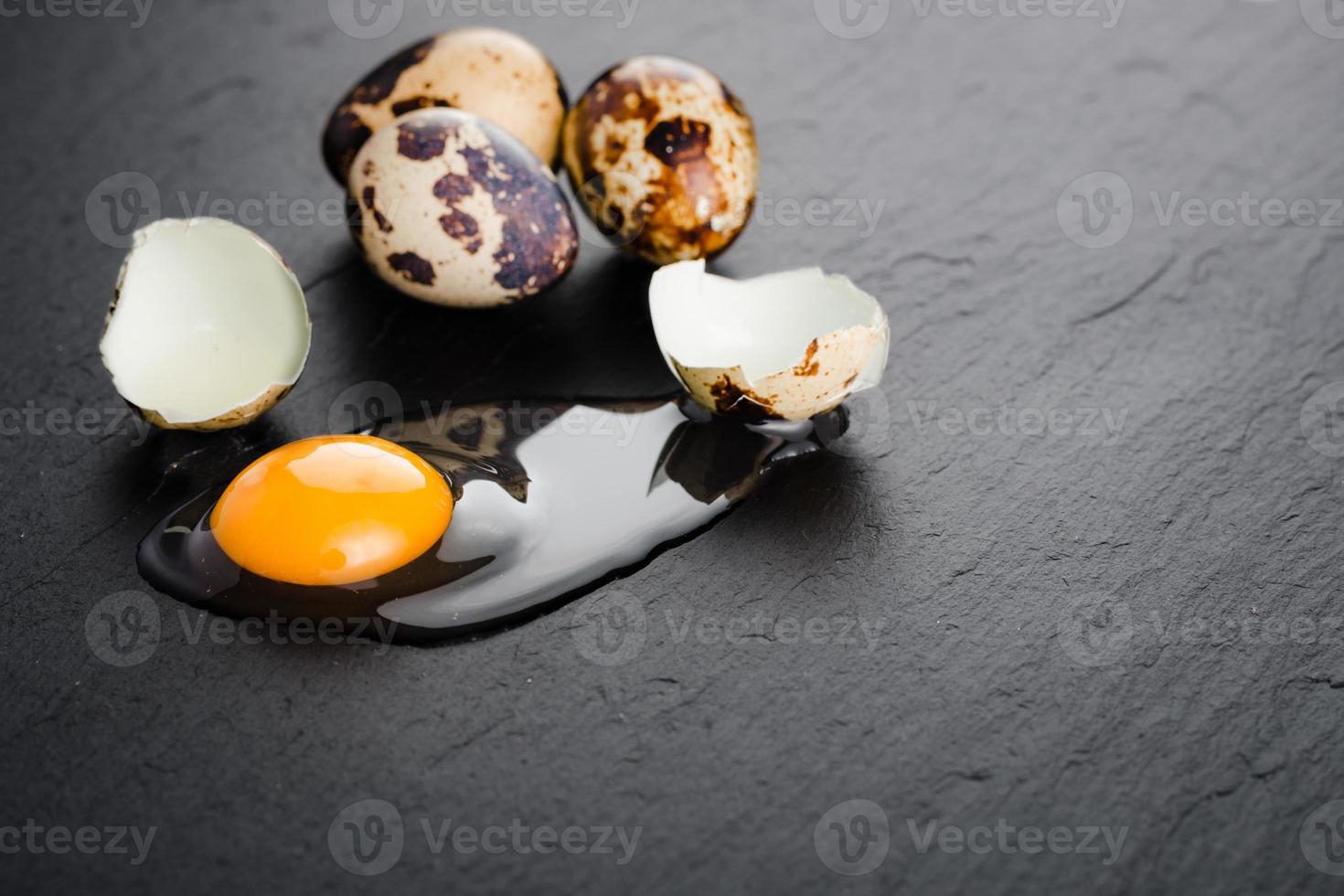 huevos de codorniz sobre fondo de piedra negra, huevo de codorniz roto, agrietado, yema de huevo de codorniz. Producto organico. foto