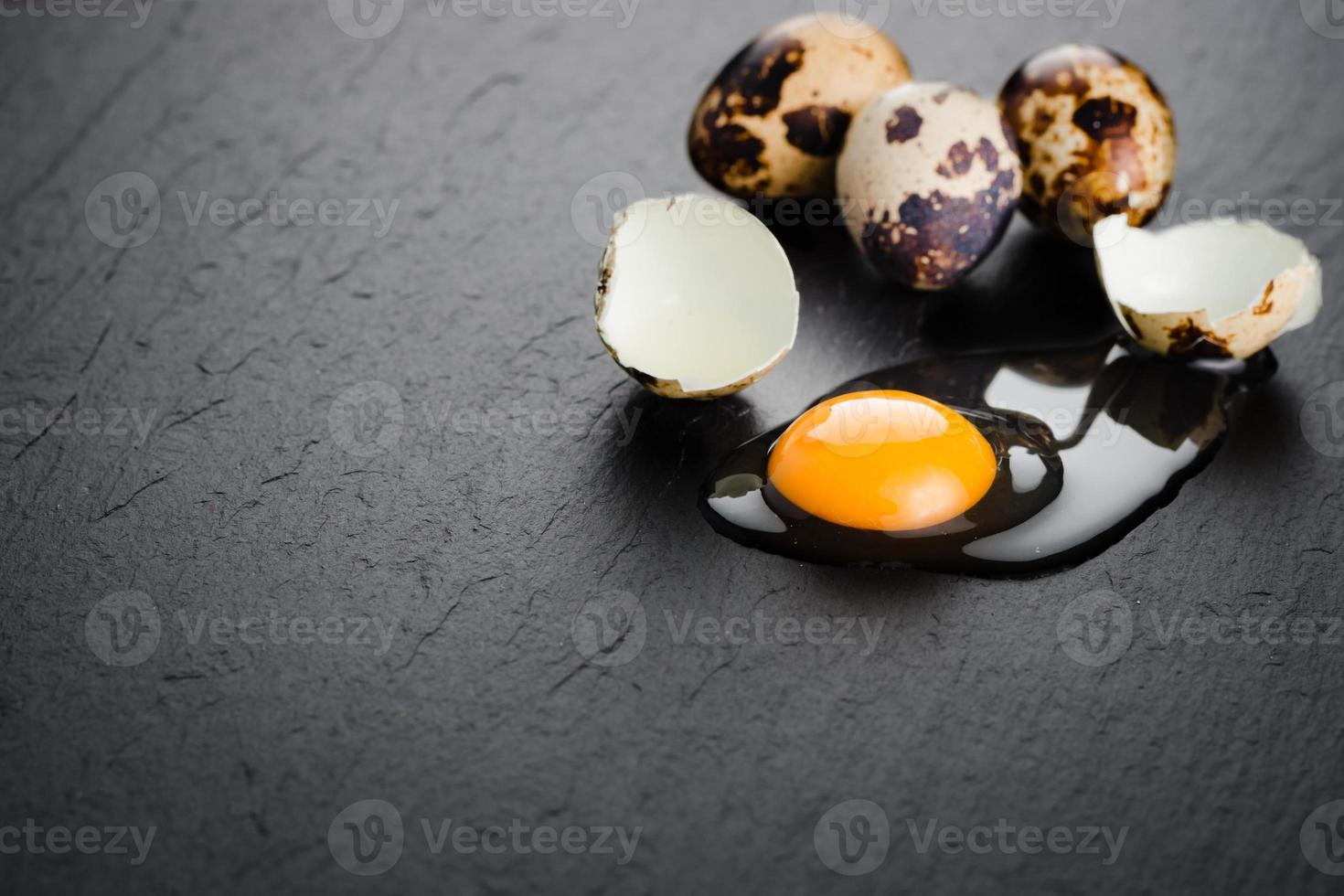 Quail eggs on black stone background, broken, cracked quail egg, yolk of quail egg. Organic product. photo