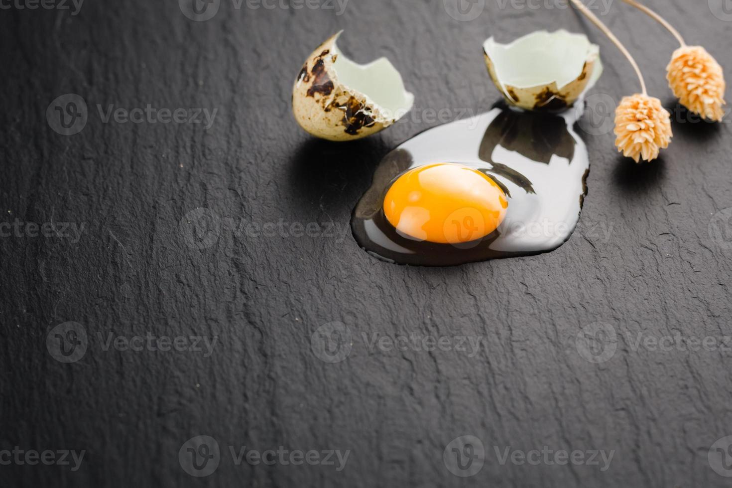 Quail eggs on black stone background, broken, cracked quail egg, yolk of quail egg. Organic product. photo