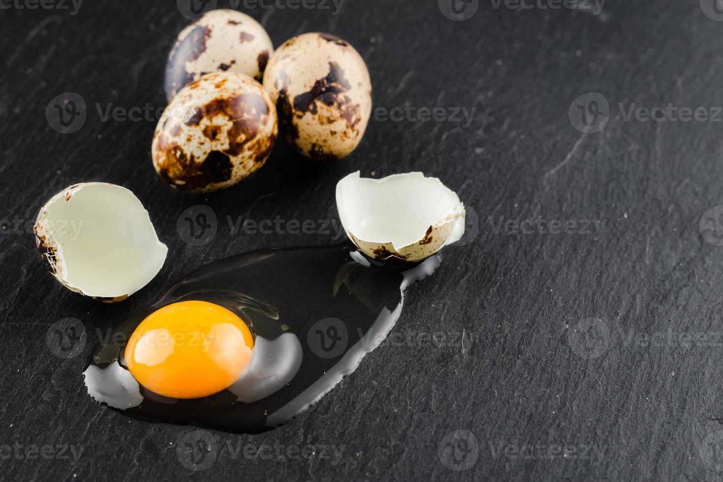 Quail eggs on black stone background, broken, cracked quail egg, yolk of quail egg. Organic product. photo