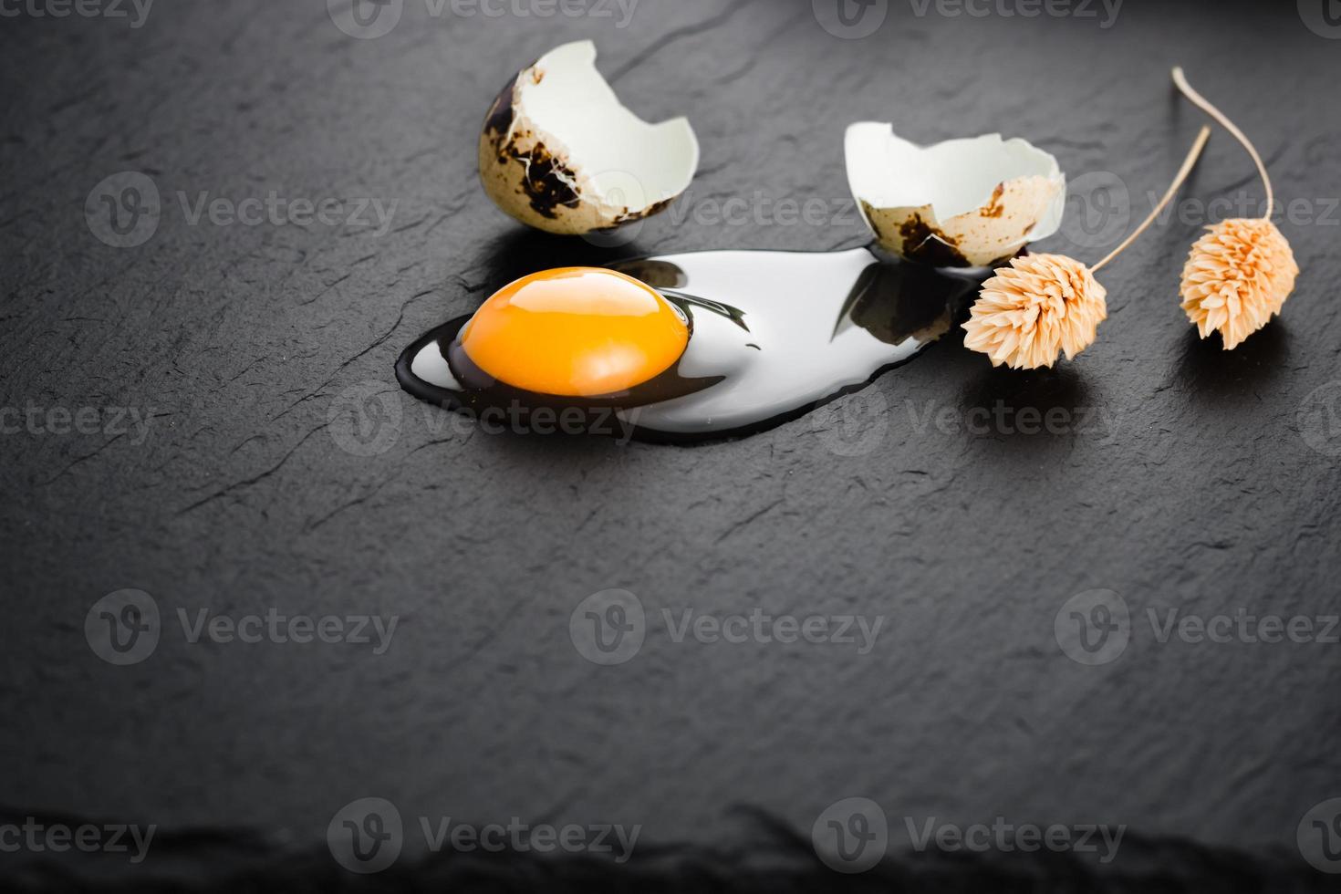 Quail eggs on black stone background, broken, cracked quail egg, yolk of quail egg. Organic product. photo