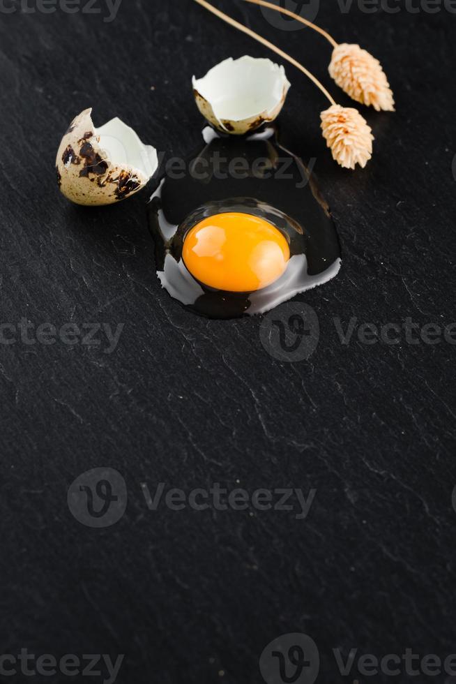 Quail eggs on black stone background, broken, cracked quail egg, yolk of quail egg. Organic product. photo