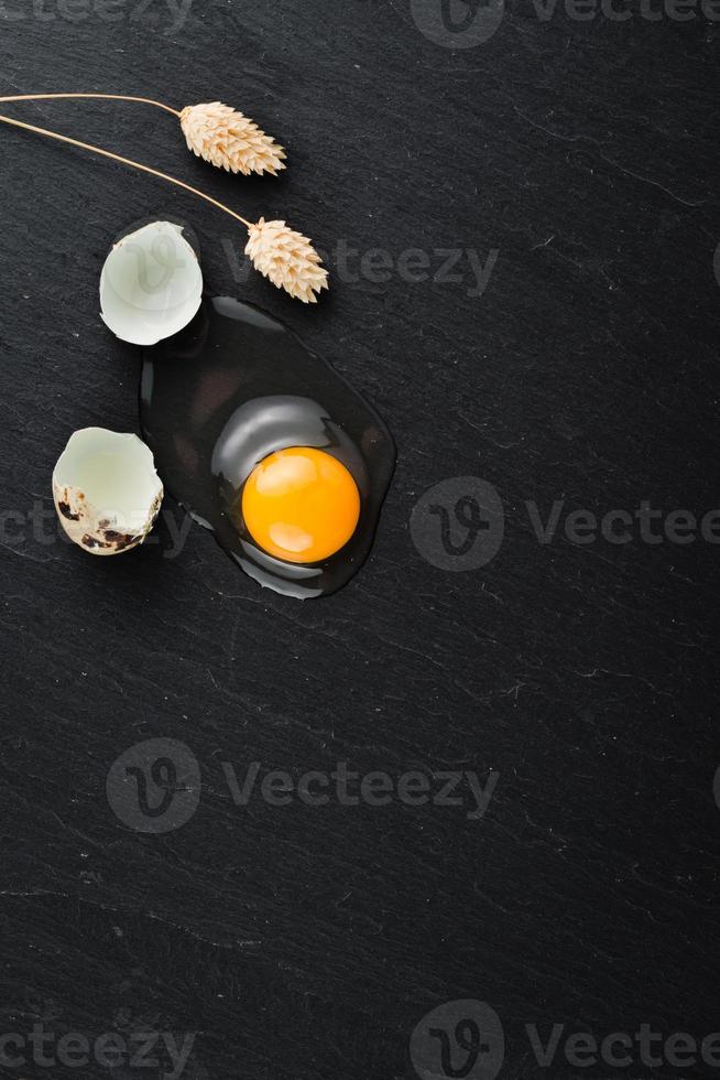 huevos de codorniz sobre fondo de piedra negra, huevo de codorniz roto, agrietado, yema de huevo de codorniz. Producto organico. foto