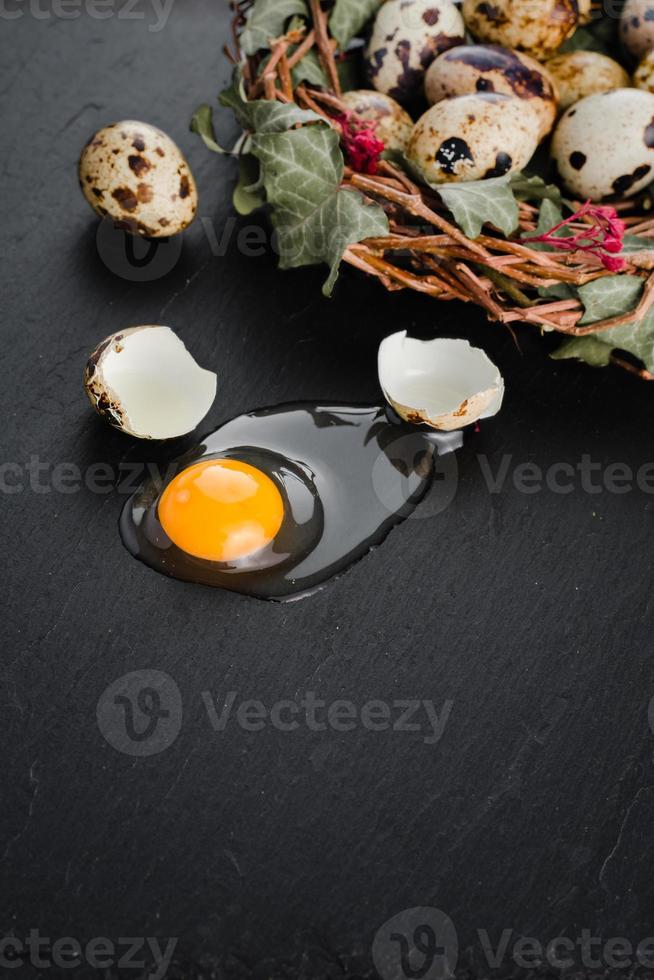 Quail eggs on black stone background, broken, cracked quail egg, yolk of quail egg. Organic product. photo