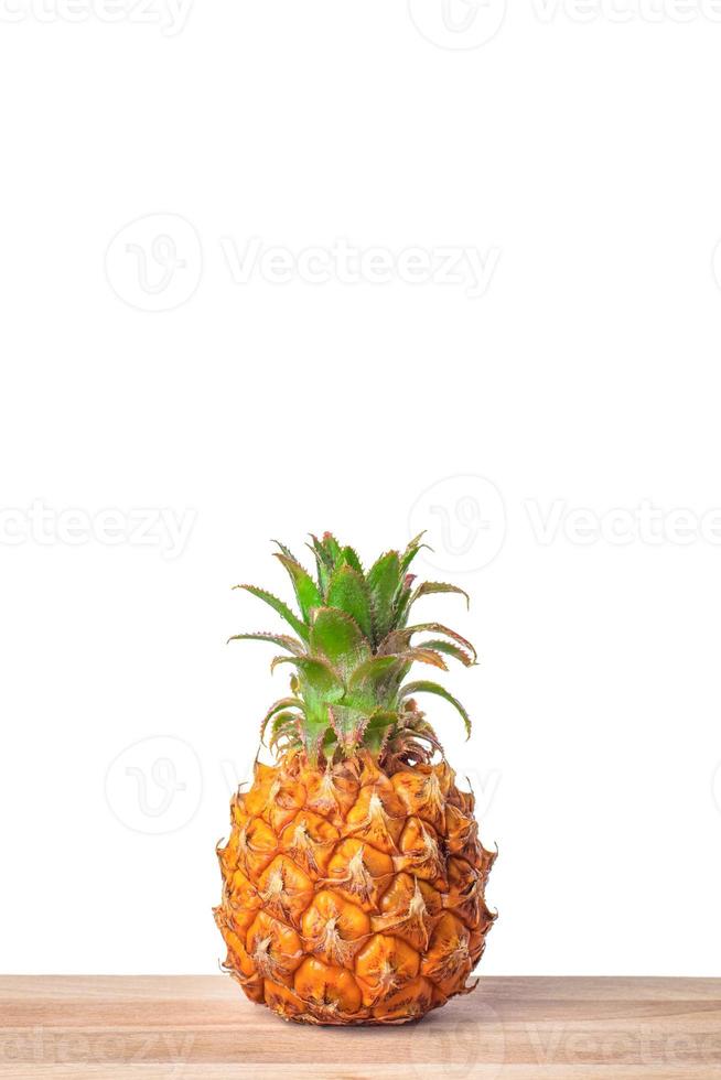 Baby pineapple on wooden table with isolated white background. photo