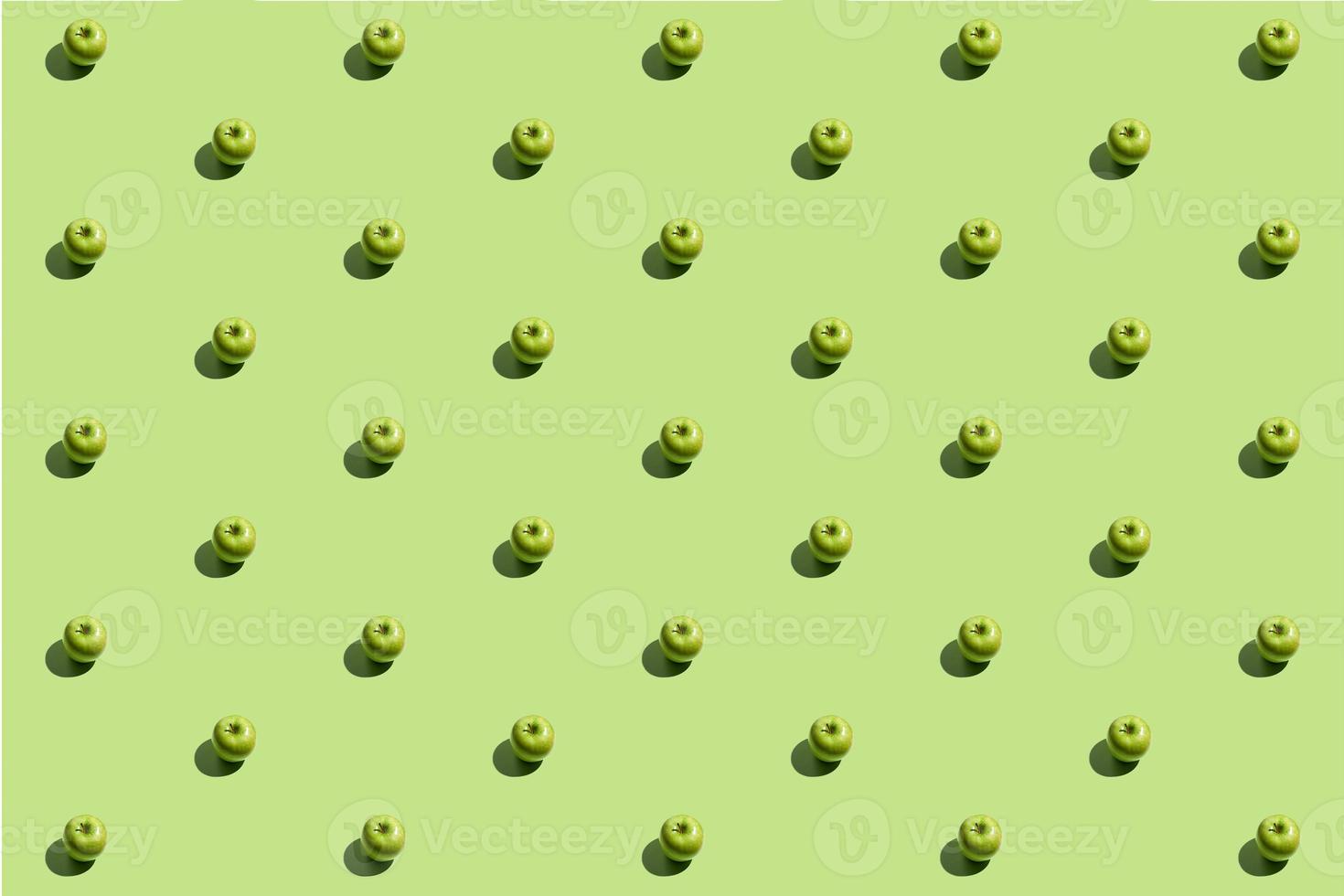 Minimal repetitive pattern made of green appes on green background photo