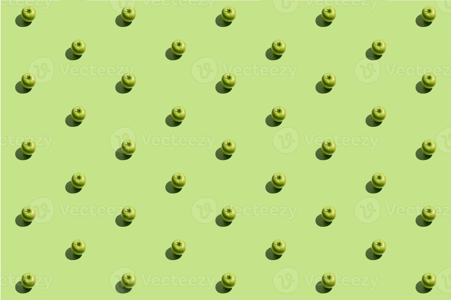 Minimal repetitive pattern made of green appes on green background photo