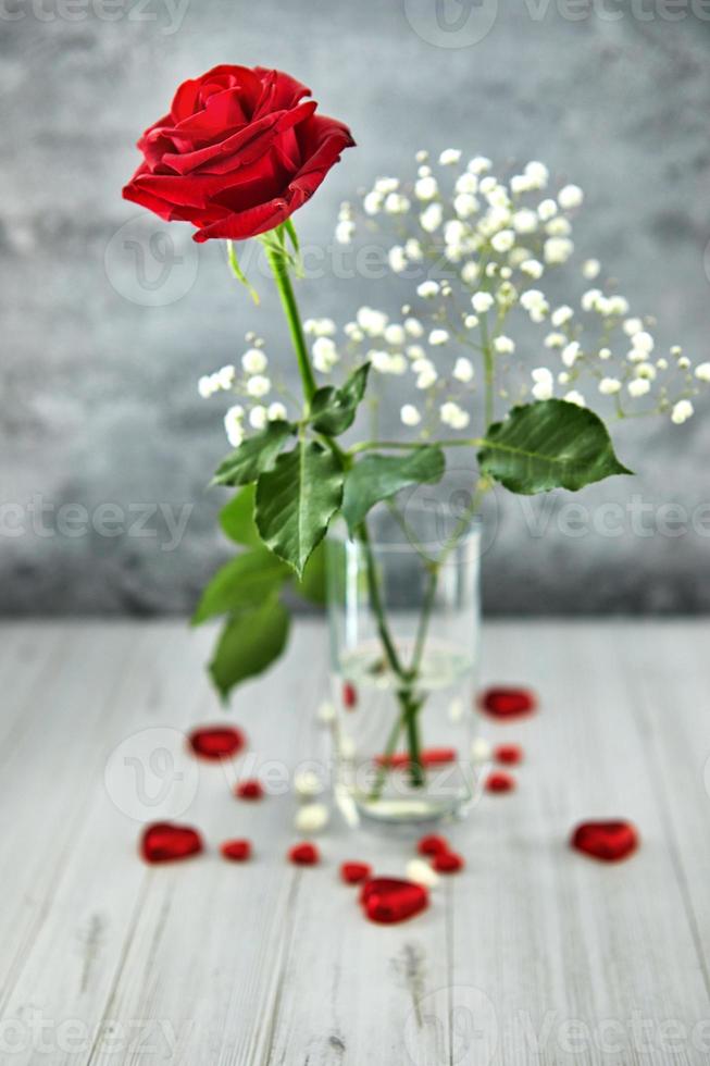 Romantic still life, red rose, chocolate in the shape of hearts on a light background. Valentine's Day concept. Soft focus photo