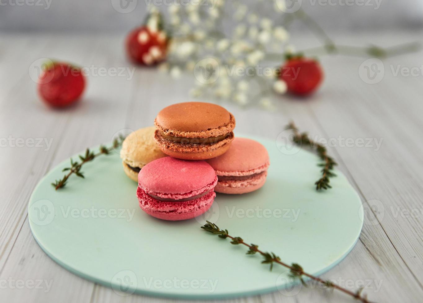 French colorful macaroons. Colorful pastel macaroons on a light background with fresh strawberries. Concept soft focus. photo
