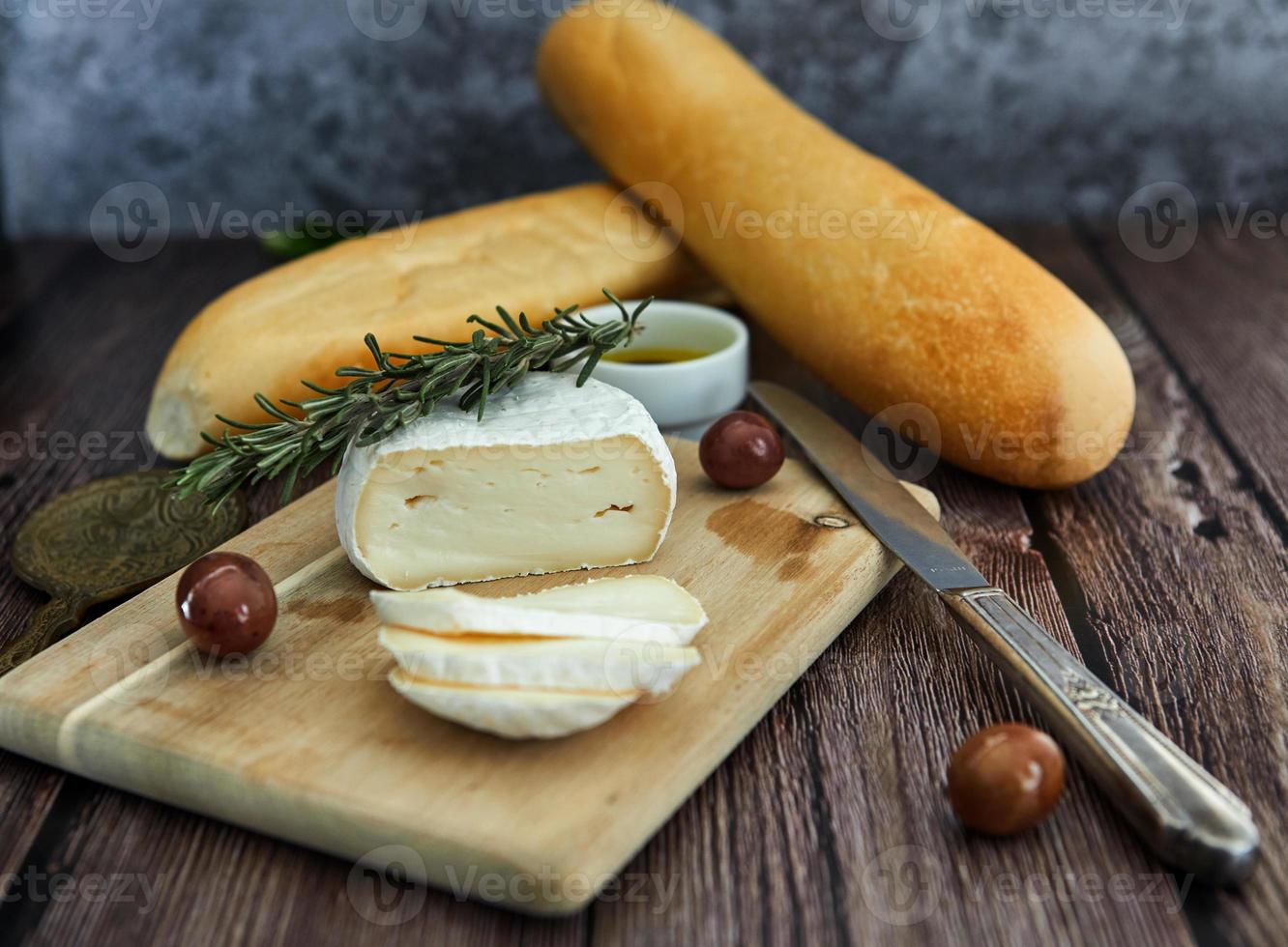 Cheese on wooden table with olives and bread photo