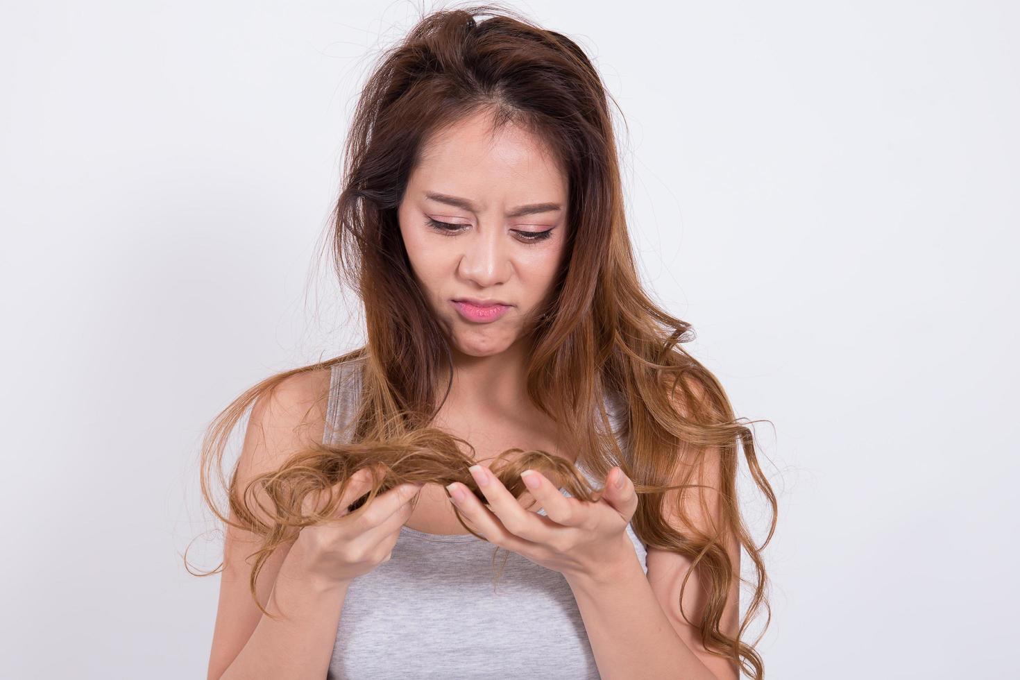 mujer asiática preocupada por la caída del cabello sobre fondo blanco. foto