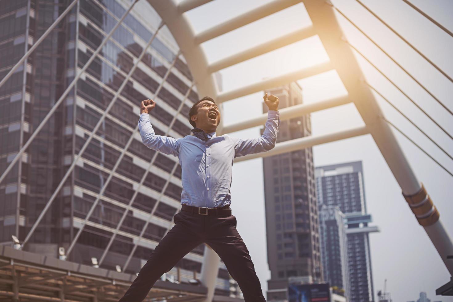 Happy Asian businessman jumping in the city after success business deal photo