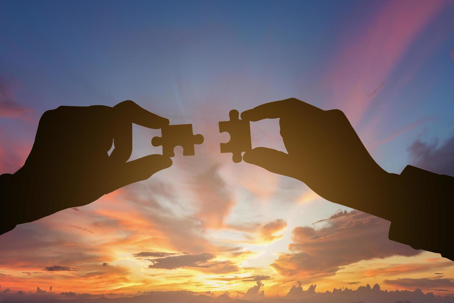 Silhouette of businesspeople hands connecting puzzle. Business teamwork concept. photo