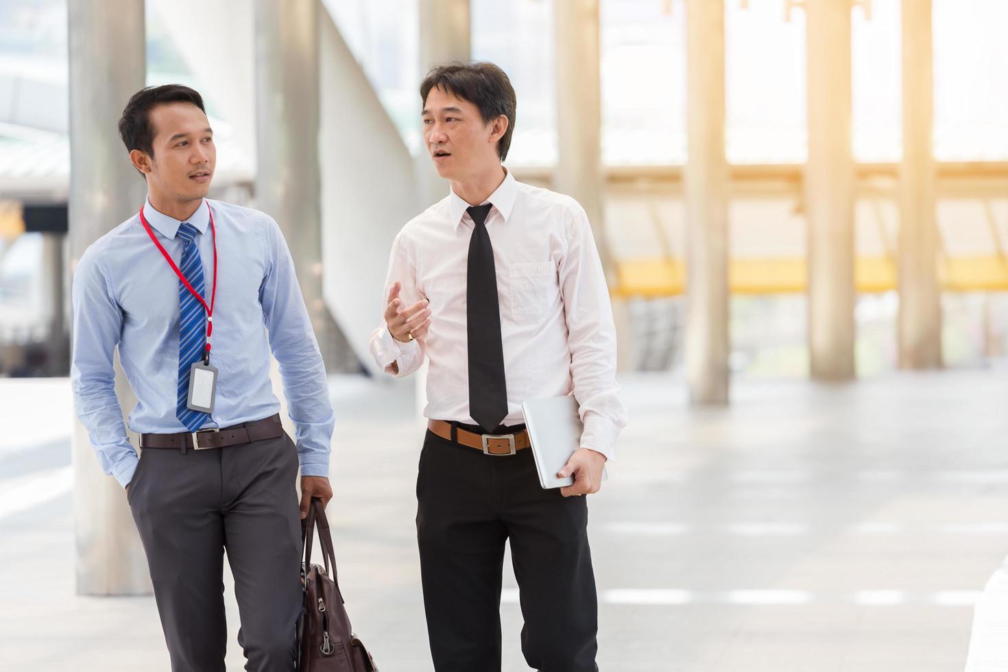 Two businessmen are working on sidewalk with smart phone and notebook for business concept. photo