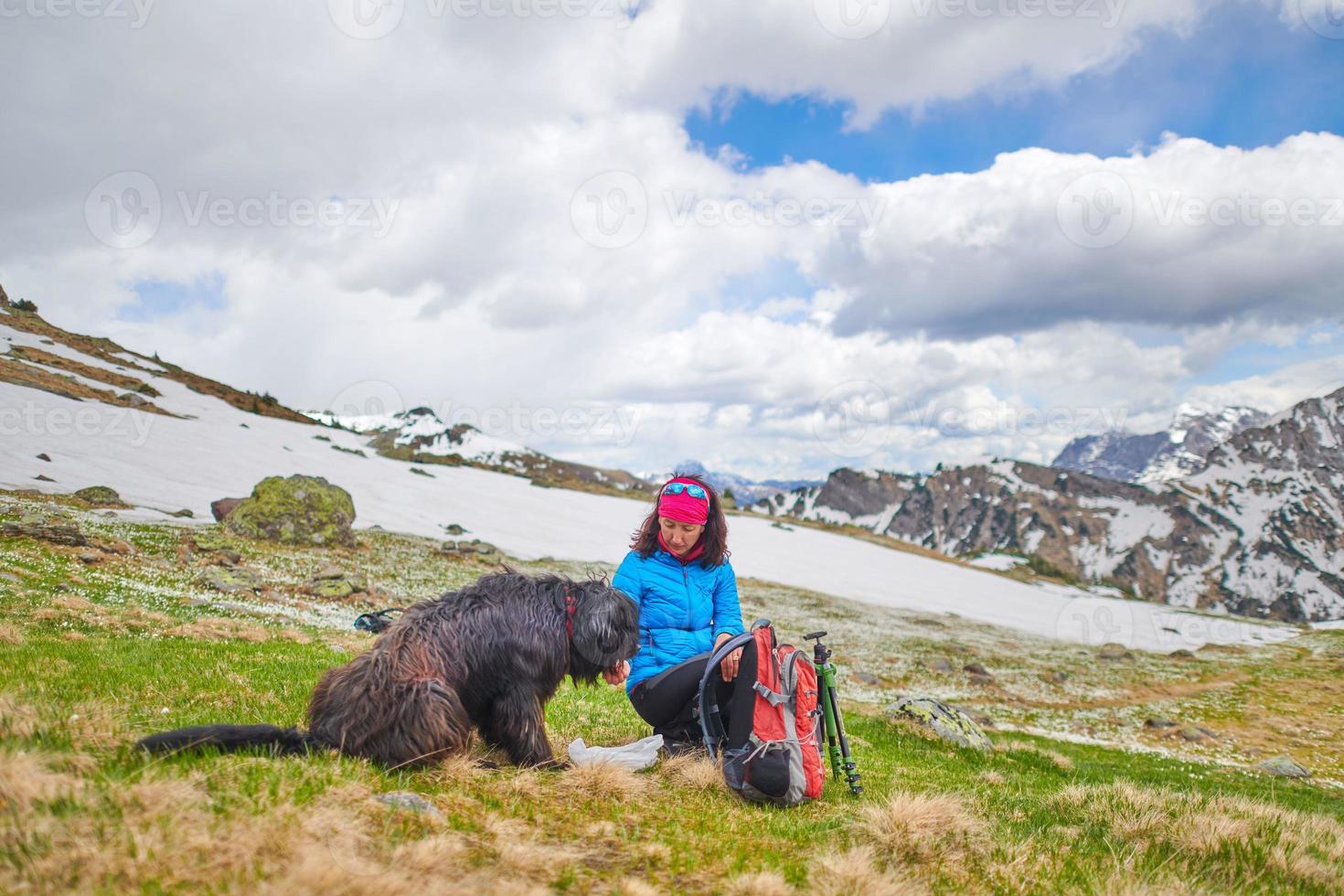A woman from food to her dog during a walk in the mountains photo