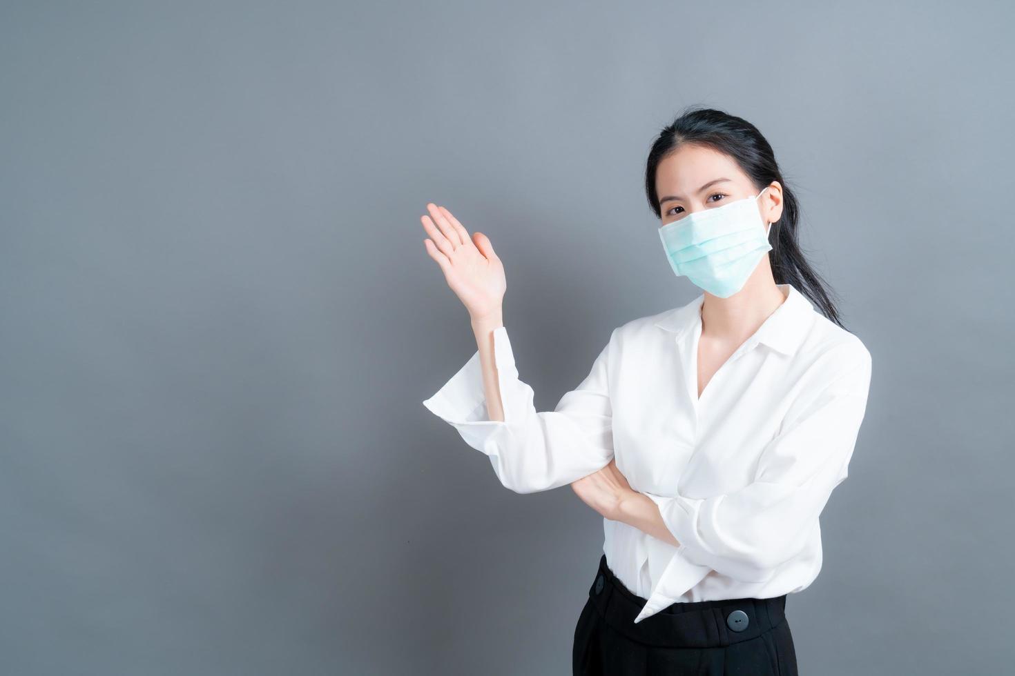 Asian woman wearing medical face mask protects filter dust and COVID 19 with hand presenting photo
