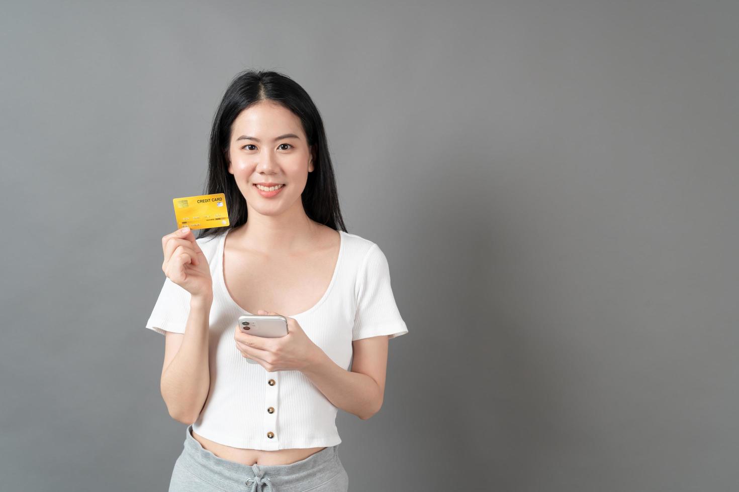 Mujer asiática con cara feliz y presentando tarjeta de crédito en mano mostrando confianza y seguridad para realizar el pago foto