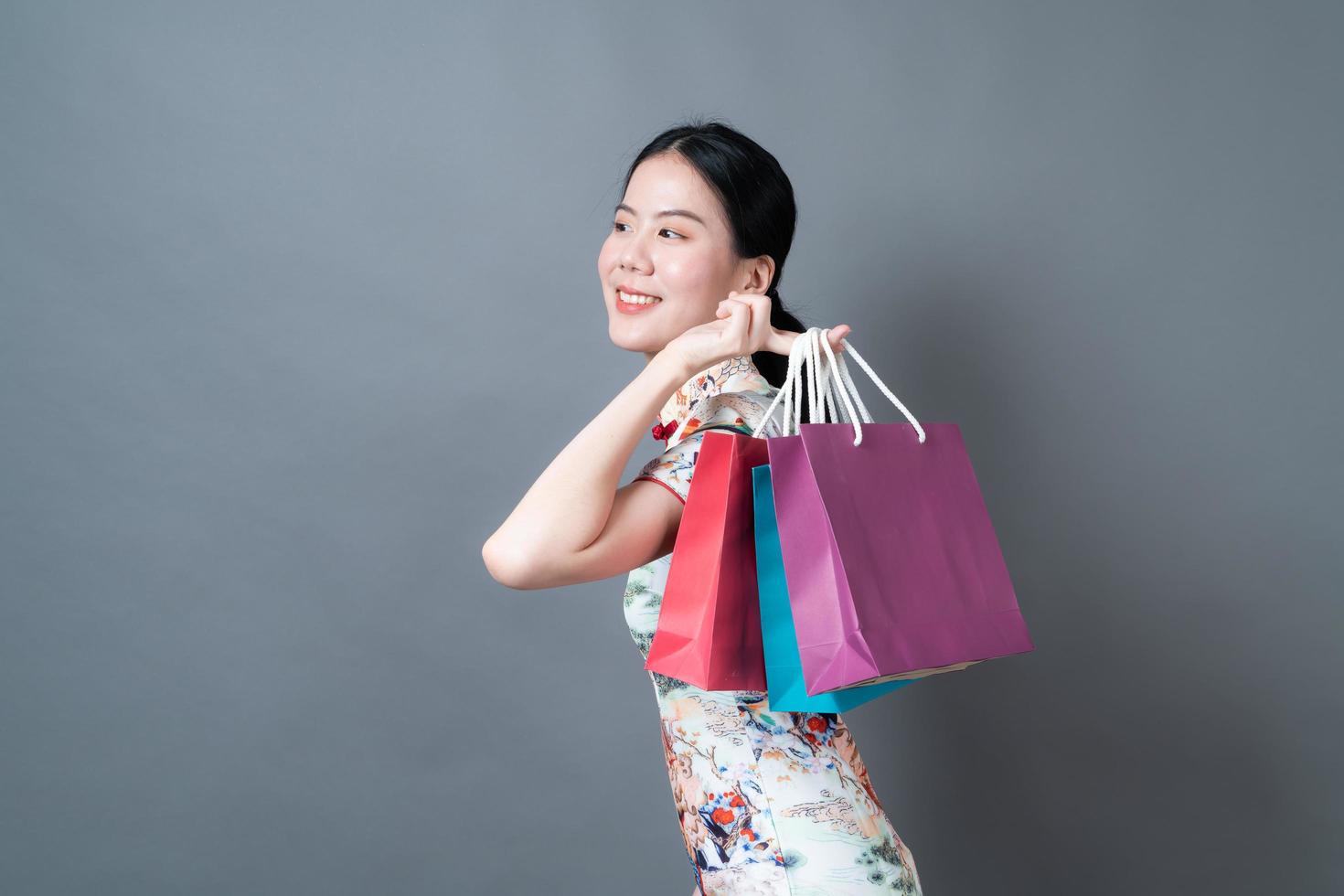 Mujer asiática vistiendo traje tradicional chino con mano sujetando la bolsa de compras foto